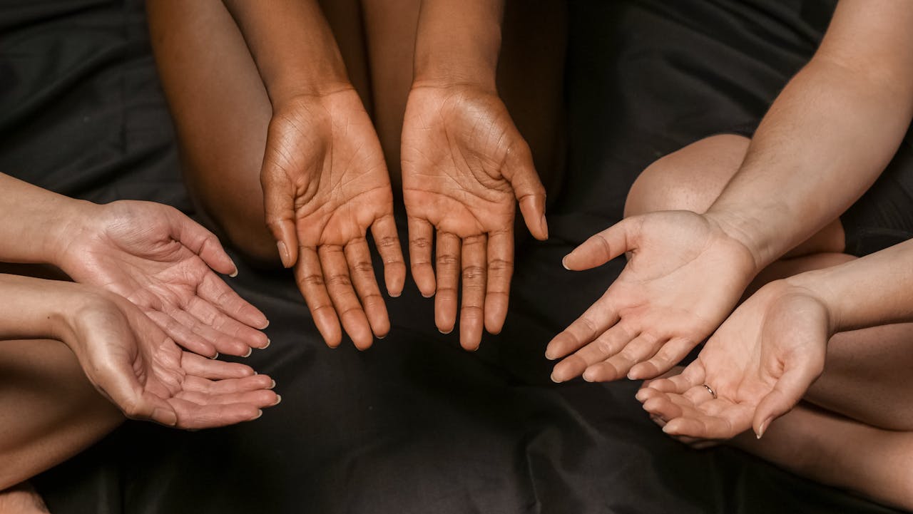 services-01 A close-up of diverse hands in a circular formation on a dark surface.