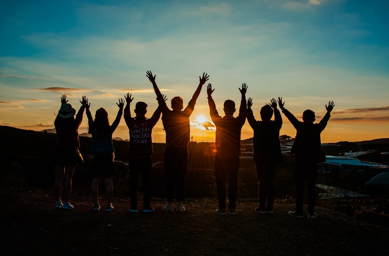 heros-img A diverse group of friends raises their arms in celebration against a vibrant sunset backdrop.
